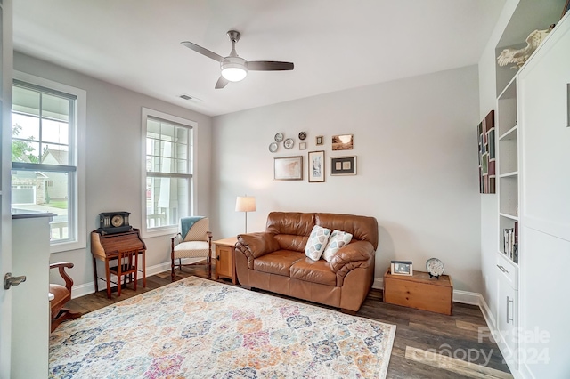 living area with ceiling fan, plenty of natural light, and dark wood-type flooring