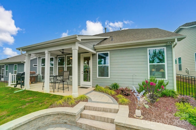 rear view of house with a patio, ceiling fan, and a lawn