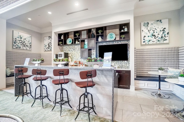 interior space featuring light stone counters, a kitchen bar, and decorative backsplash