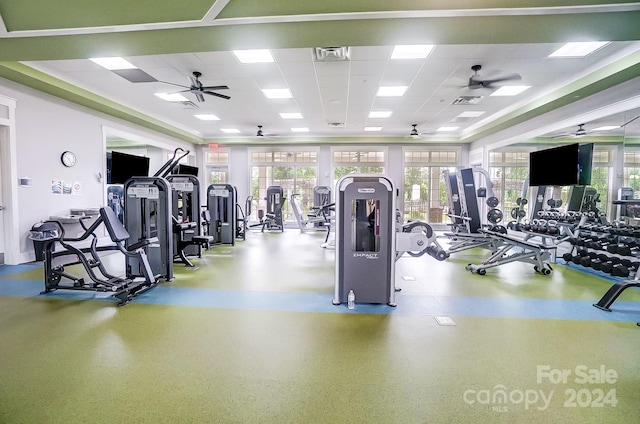 exercise room with ceiling fan, plenty of natural light, and a drop ceiling