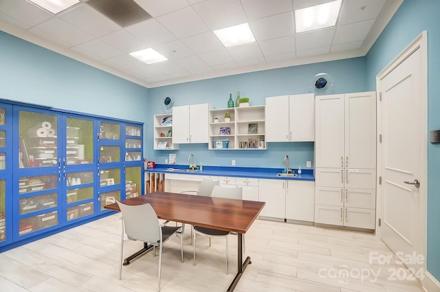 kitchen featuring a drop ceiling, sink, and white cabinets