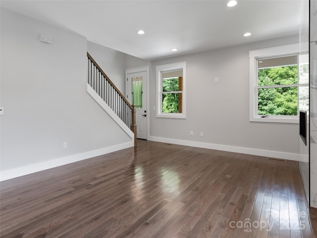 unfurnished room with stairs, baseboards, and dark wood-style flooring