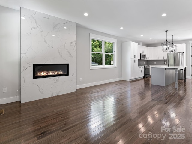 unfurnished living room featuring recessed lighting, a fireplace, a sink, visible vents, and dark wood finished floors