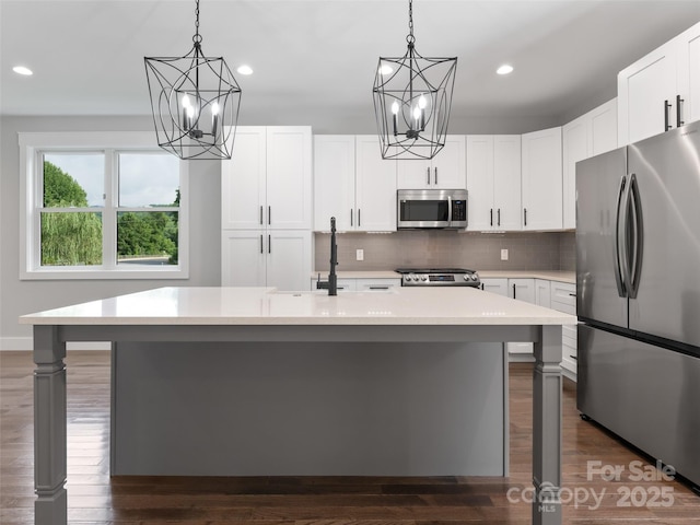 kitchen with stainless steel appliances, light countertops, and a kitchen island with sink