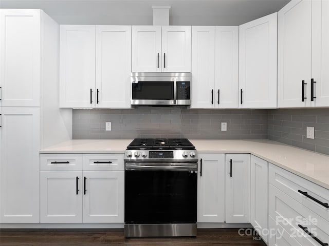 kitchen with appliances with stainless steel finishes, white cabinets, and backsplash