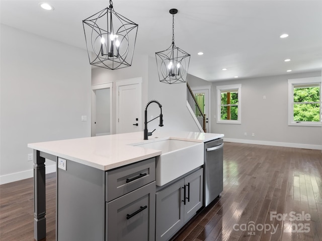 kitchen with a center island with sink, dishwasher, hanging light fixtures, gray cabinetry, and a sink