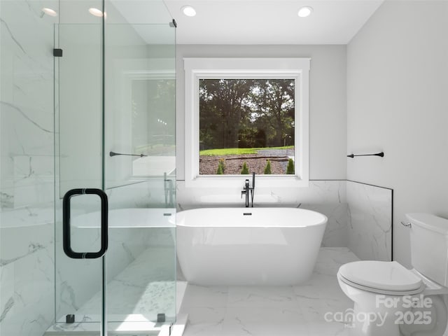 bathroom featuring toilet, marble finish floor, a freestanding tub, a shower stall, and recessed lighting