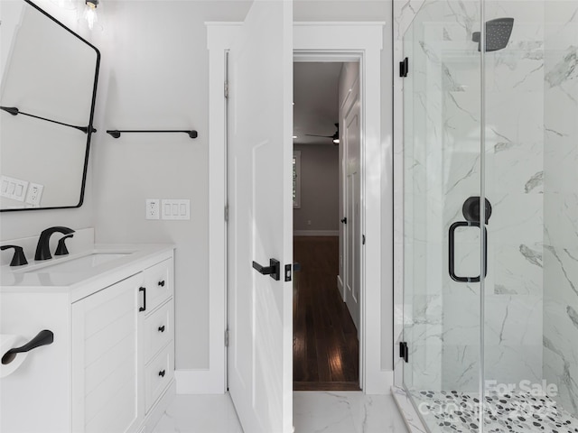 full bath with marble finish floor, a marble finish shower, baseboards, and vanity