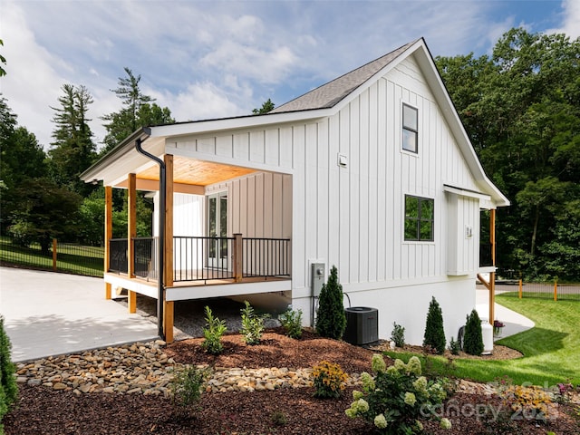 exterior space featuring a porch, board and batten siding, and cooling unit