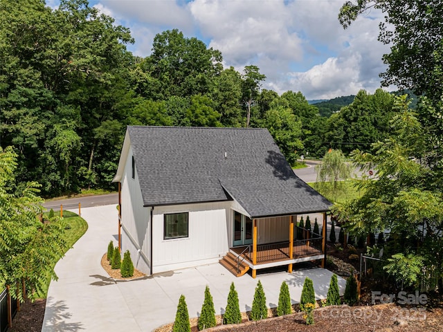 view of front of home with roof with shingles and a wooden deck