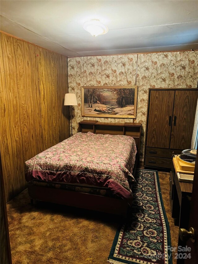 bedroom featuring dark carpet and wooden walls