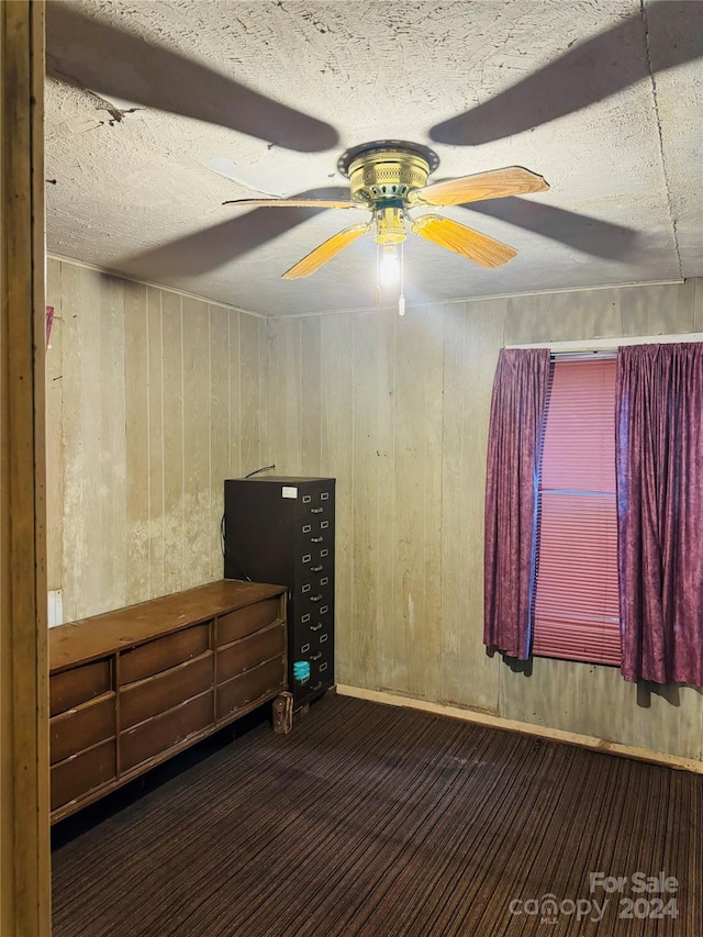 unfurnished bedroom with ceiling fan, a textured ceiling, and wood walls