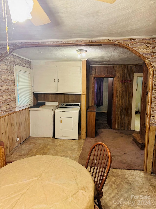 interior space with light colored carpet, washer and dryer, wooden walls, and ceiling fan