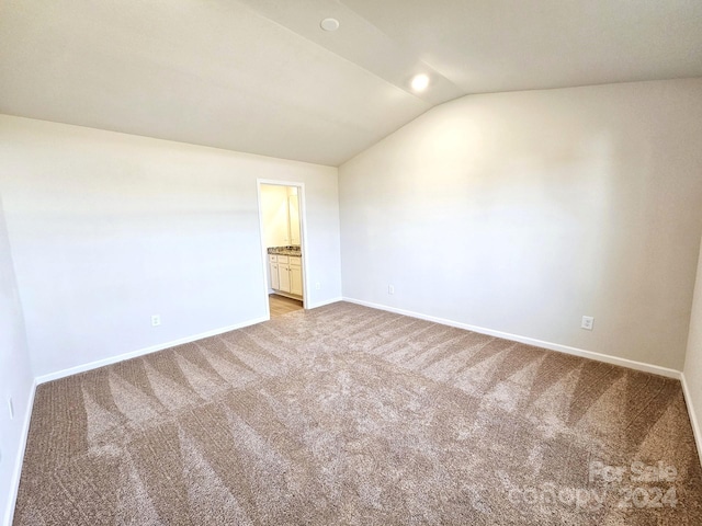 carpeted empty room featuring lofted ceiling