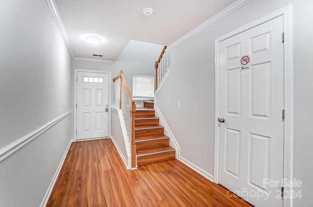 stairs with light hardwood / wood-style floors and ornamental molding