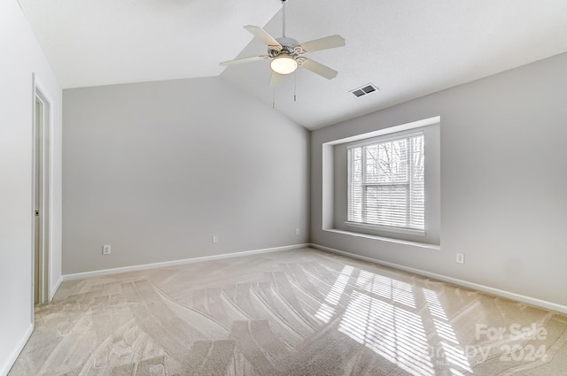 empty room featuring light carpet, vaulted ceiling, and ceiling fan