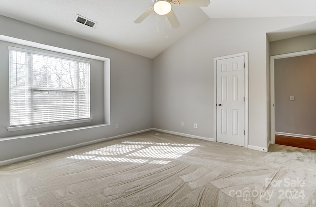 carpeted spare room featuring ceiling fan and vaulted ceiling