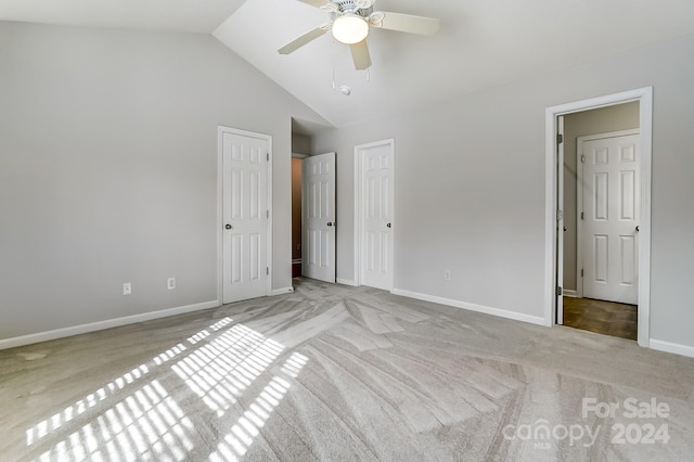 unfurnished bedroom with light carpet, two closets, high vaulted ceiling, and ceiling fan