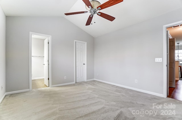 unfurnished bedroom featuring connected bathroom, ceiling fan, light carpet, vaulted ceiling, and a closet