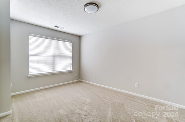 carpeted empty room featuring a textured ceiling