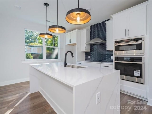 kitchen with white cabinets, dark hardwood / wood-style flooring, an island with sink, and sink