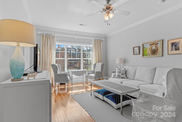 living room with ceiling fan, crown molding, and light wood-type flooring