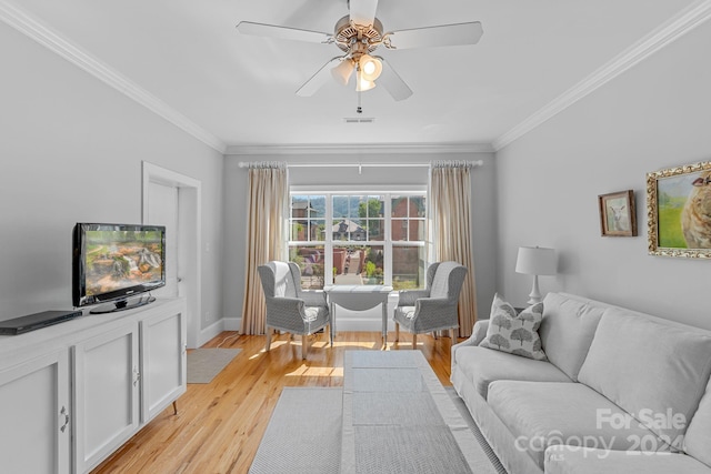 living room featuring visible vents, light wood-style flooring, ornamental molding, a ceiling fan, and baseboards