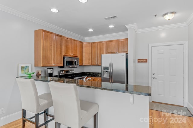 kitchen with stainless steel appliances, visible vents, dark stone countertops, a peninsula, and a kitchen breakfast bar