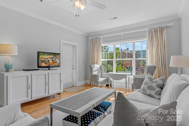 living area with visible vents, light wood-style flooring, ornamental molding, and a ceiling fan