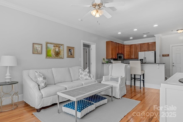 living room with light wood finished floors, baseboards, ceiling fan, and ornamental molding