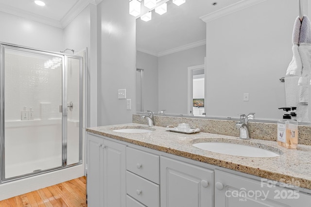 full bath with a stall shower, ornamental molding, and a sink