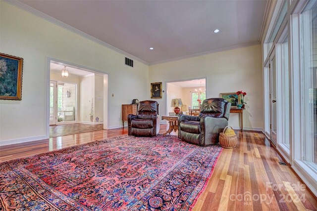 living room with ornamental molding, light hardwood / wood-style flooring, and a healthy amount of sunlight