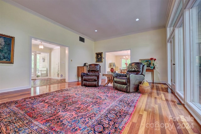 living room with crown molding, hardwood / wood-style floors, and an inviting chandelier