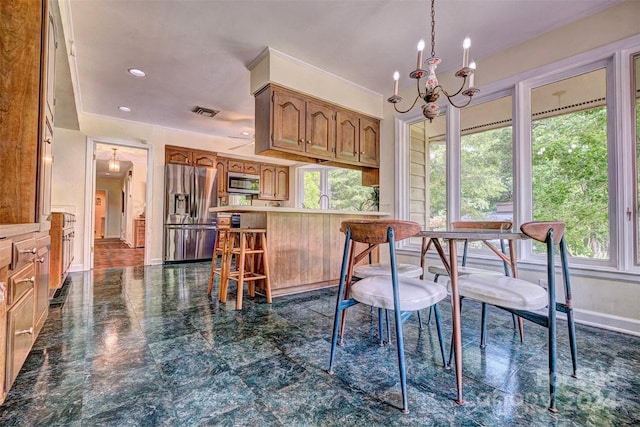 kitchen featuring dark tile patterned floors, stainless steel appliances, a notable chandelier, and a breakfast bar area