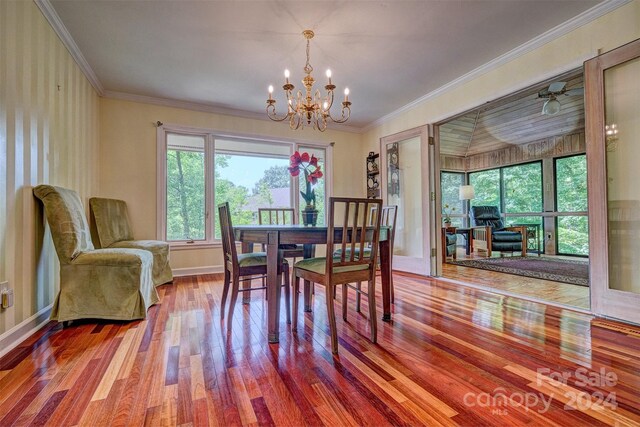 dining space with hardwood / wood-style flooring, crown molding, and a chandelier