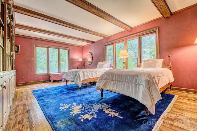 bedroom with light hardwood / wood-style flooring and beam ceiling