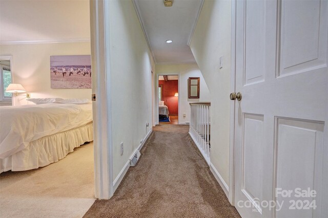 hall with ornamental molding and light colored carpet