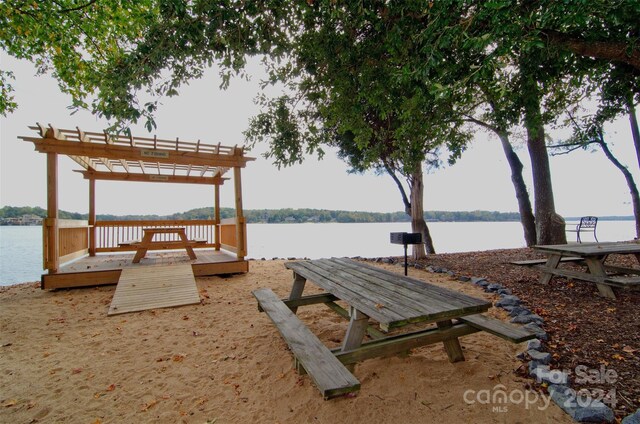 view of dock with a pergola and a water view