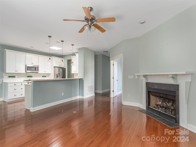 kitchen featuring appliances with stainless steel finishes, kitchen peninsula, hardwood / wood-style floors, and white cabinetry