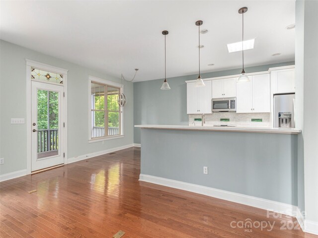 kitchen with white cabinetry, tasteful backsplash, hardwood / wood-style floors, and stainless steel appliances