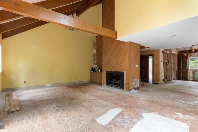 unfurnished living room featuring beam ceiling, a large fireplace, and high vaulted ceiling