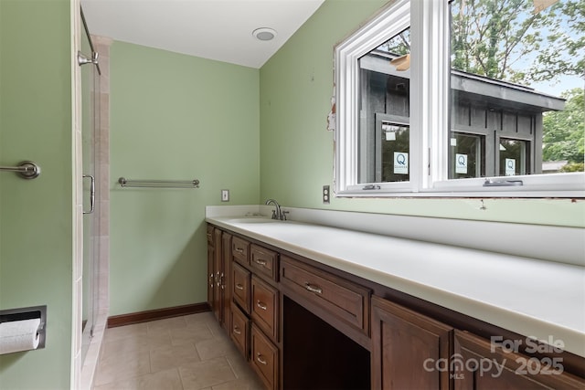 bathroom with a shower with shower door, a healthy amount of sunlight, tile patterned flooring, and vanity