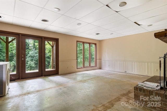 unfurnished room with a healthy amount of sunlight, a paneled ceiling, and concrete floors