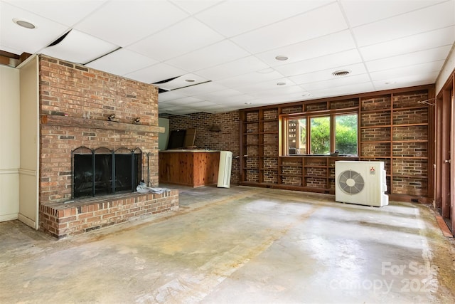 unfurnished living room with concrete floors, brick wall, a paneled ceiling, and a fireplace