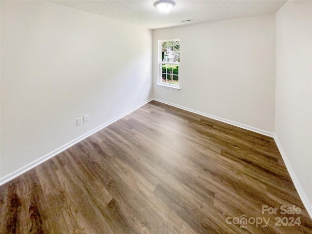 empty room featuring a textured ceiling and wood-type flooring