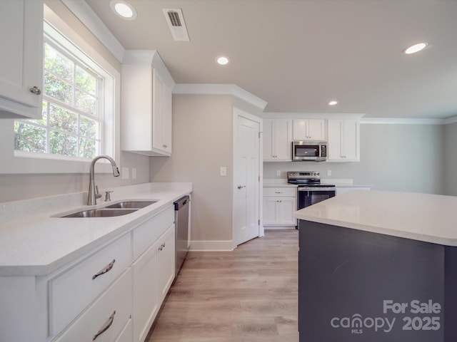 kitchen with sink, white cabinetry, crown molding, light wood-type flooring, and stainless steel appliances