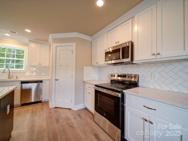 1133 Heather Oak Ln, Oakboro, NC 28129 - kitchen with appliances with stainless steel finishes, tasteful backsplash, white cabinets, light wood-type flooring, and recessed lighting