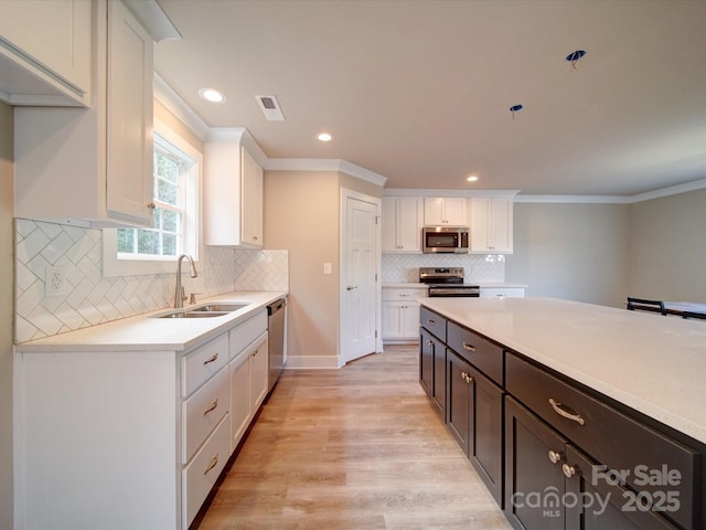 1133 Heather Oak Ln, Oakboro, NC 28129 - kitchen featuring a sink, appliances with stainless steel finishes, white cabinetry, light countertops, and light wood finished floors