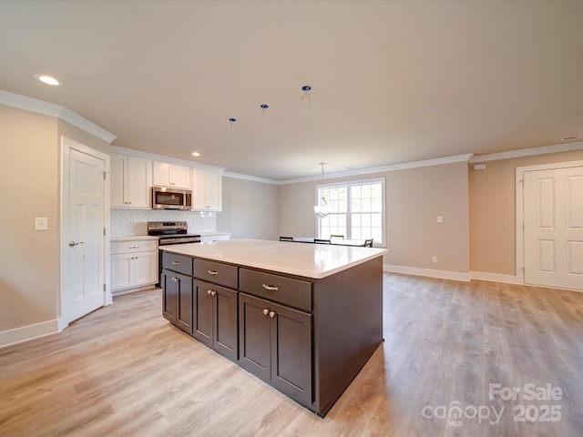 1133 Heather Oak Ln, Oakboro, NC 28129 - kitchen featuring stainless steel appliances, ornamental molding, white cabinetry, light wood-style floors, and a center island