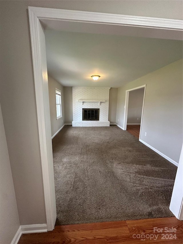 unfurnished living room featuring a fireplace and dark colored carpet